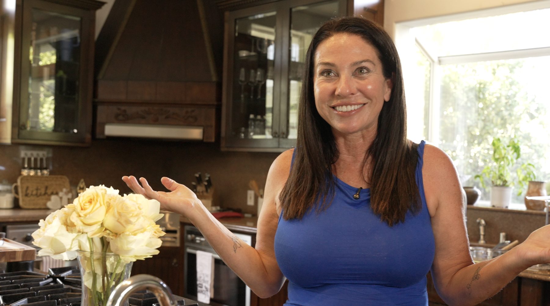 Ava Malazian smiling beside a vase of cream roses in the kitchen