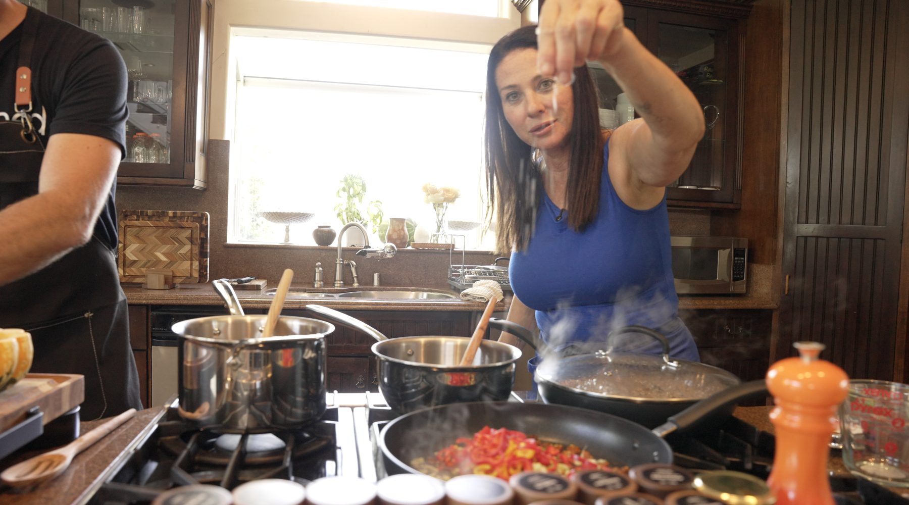 Ava Malazian seasoning a pan at the stove as steam rises
