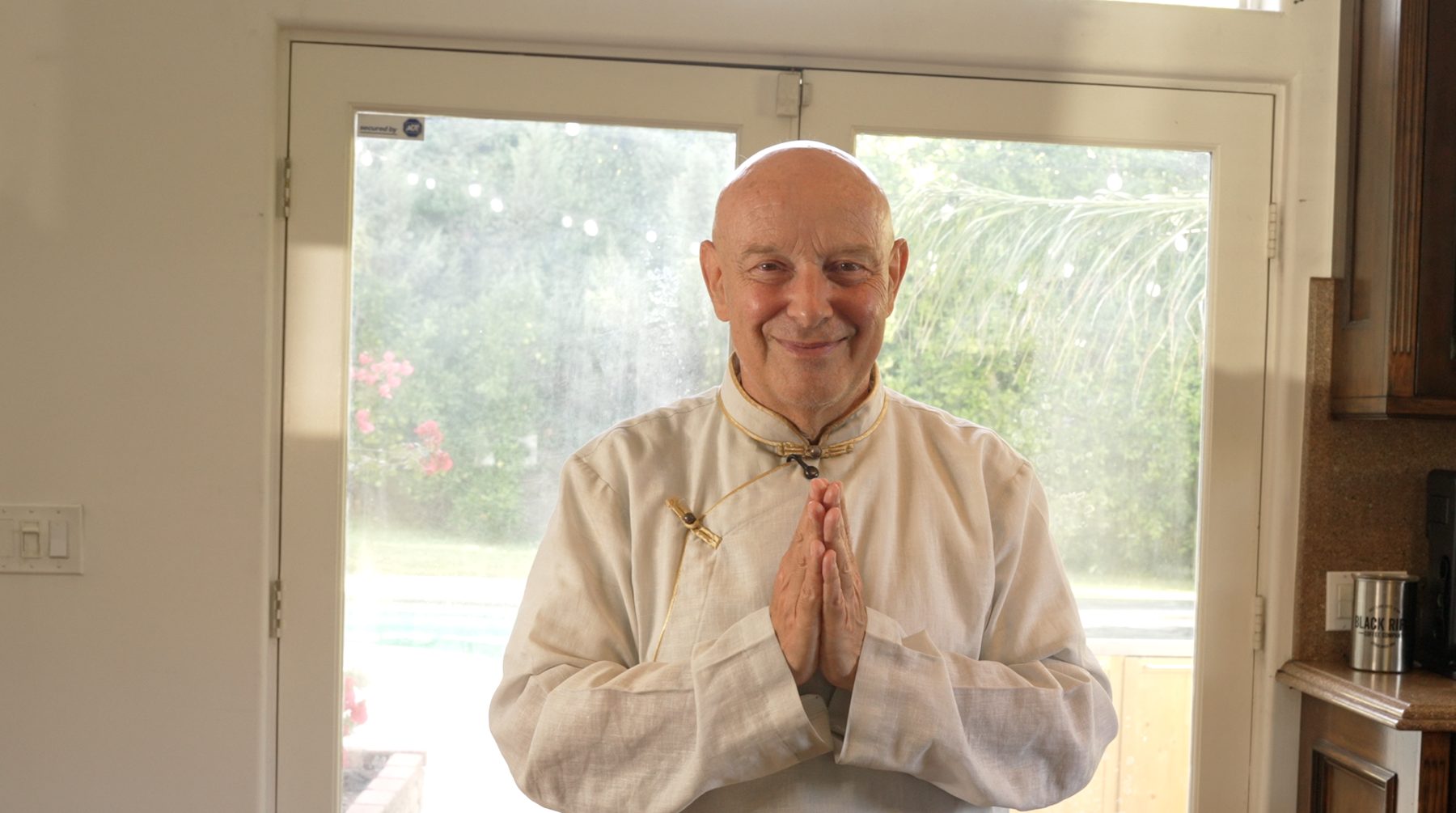Michel Pascal in a pale linen shirt at a glass door, hands together